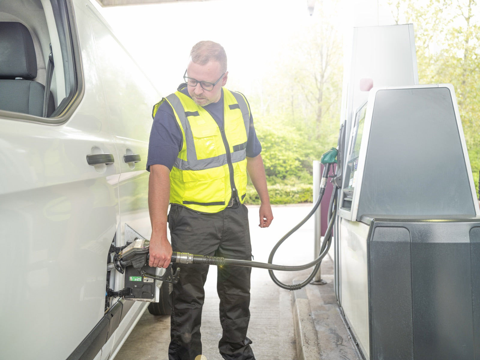Fleet driver refueling a white work van